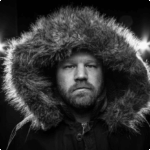 Man with a fur-lined hood in a dramatic black and white portrait, representing creativity and professionalism in marketing.