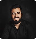 Adam Armijo, videographer and editor at Prosperia Marketing, smiling against a dark background, reflecting the agency's commitment to creativity and professionalism.