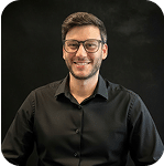 Gall Magril, member of Prosperia Marketing team, smiling and wearing glasses against a dark background.